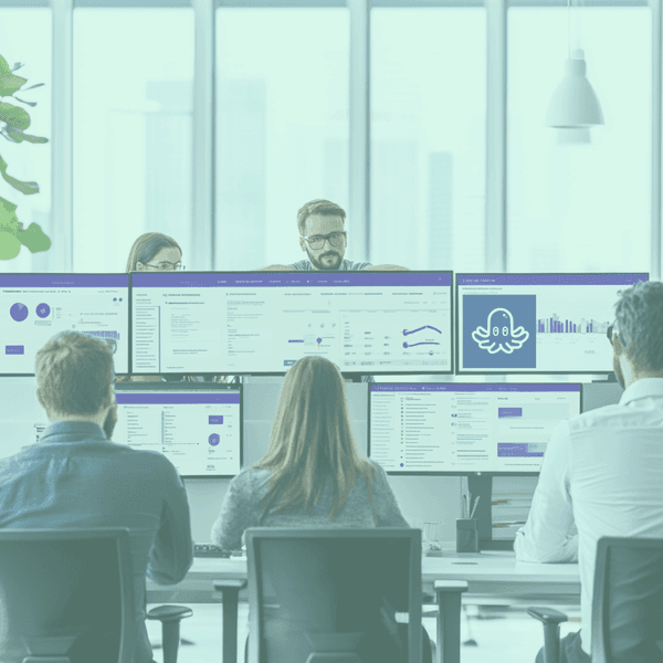 Professional team collaborating in an office setting with multiple computer screens displaying dashboards and automation tools, illustrating productivity and efficiency.